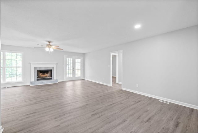 unfurnished living room with wood finished floors, a ceiling fan, and a wealth of natural light