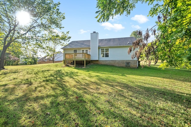 rear view of house featuring a chimney, a lawn, and a wooden deck