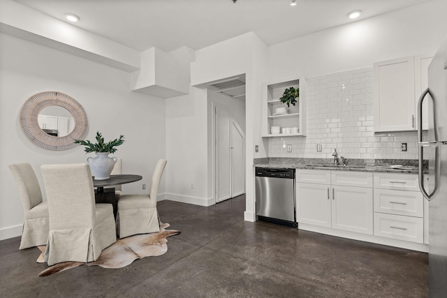 kitchen featuring a sink, stainless steel appliances, dark stone countertops, and white cabinetry