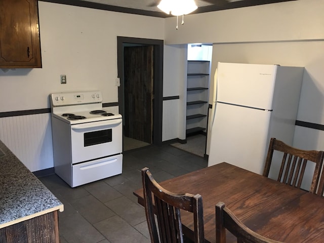 kitchen featuring white appliances, dark tile patterned flooring, ceiling fan, dark brown cabinets, and wainscoting