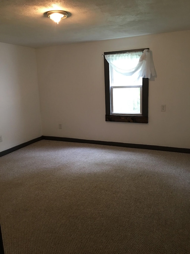 empty room featuring a textured ceiling, baseboards, and carpet floors