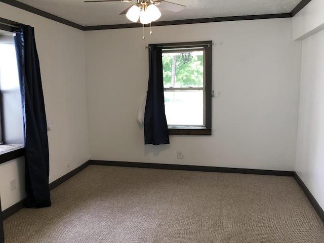 carpeted spare room with ceiling fan, baseboards, and ornamental molding