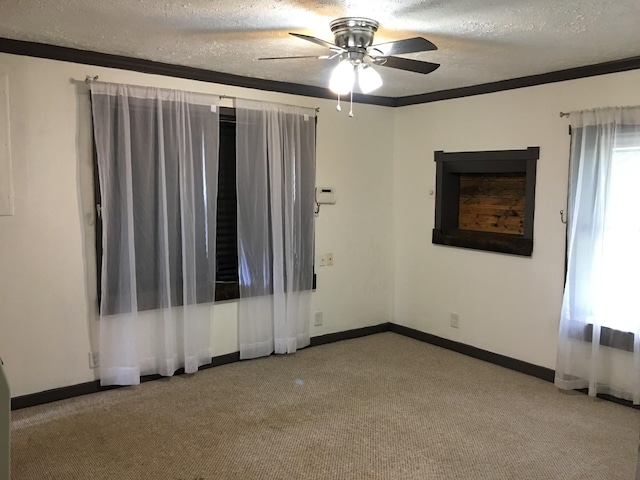 carpeted spare room featuring ceiling fan, crown molding, baseboards, and a textured ceiling