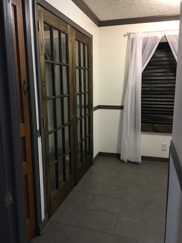 corridor with a textured ceiling, french doors, and wainscoting