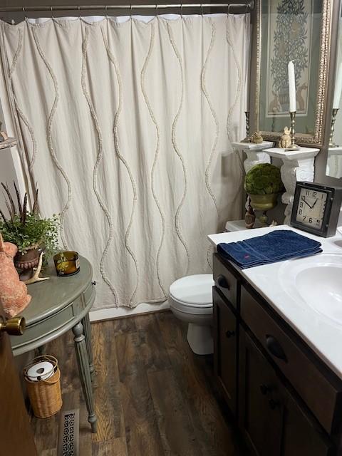 bathroom with curtained shower, toilet, vanity, and wood finished floors