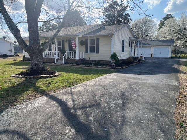 single story home featuring aphalt driveway, a garage, a porch, and a front yard