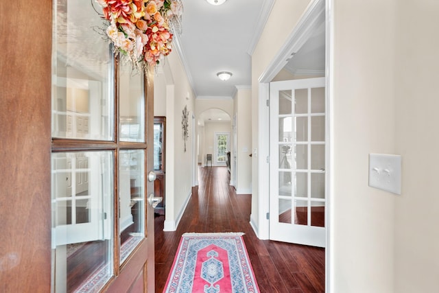 hall with baseboards, arched walkways, wood finished floors, and crown molding