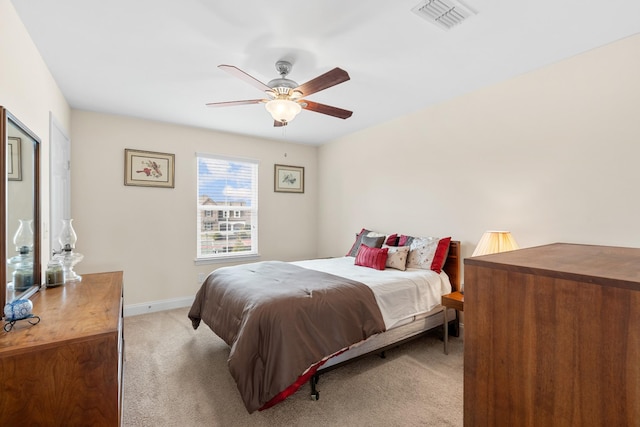 bedroom with visible vents, light colored carpet, baseboards, and ceiling fan