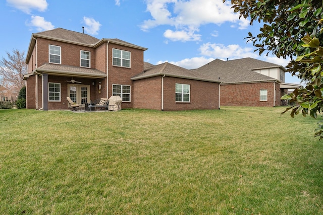 rear view of property with a yard, brick siding, ceiling fan, and a patio area