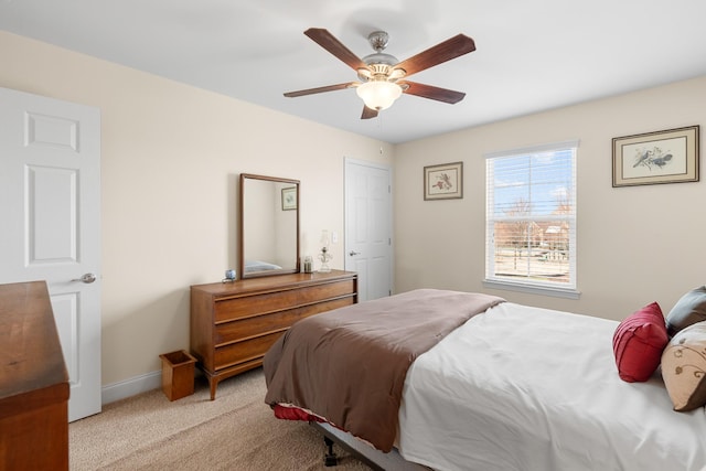 bedroom with light colored carpet, baseboards, and ceiling fan