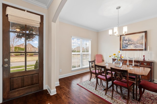 dining space with a notable chandelier, hardwood / wood-style floors, arched walkways, crown molding, and baseboards