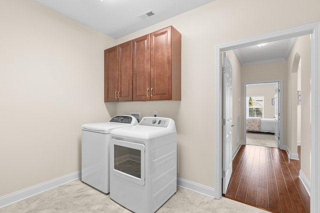 washroom with washer and dryer, cabinet space, visible vents, and baseboards