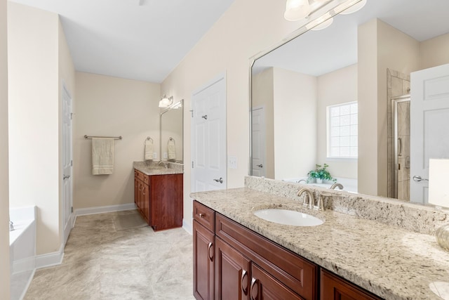 full bath featuring two vanities, a stall shower, a sink, baseboards, and a bath