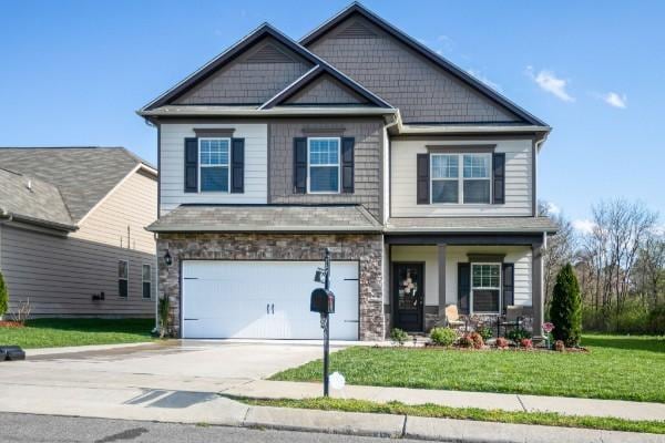 craftsman-style house with stone siding, a front yard, an attached garage, and driveway