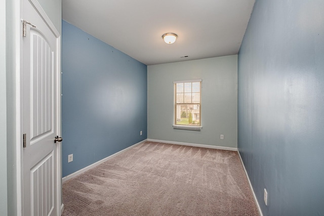 carpeted spare room featuring baseboards