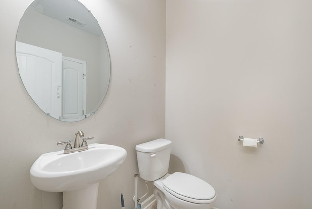 half bathroom featuring a sink, visible vents, baseboards, and toilet