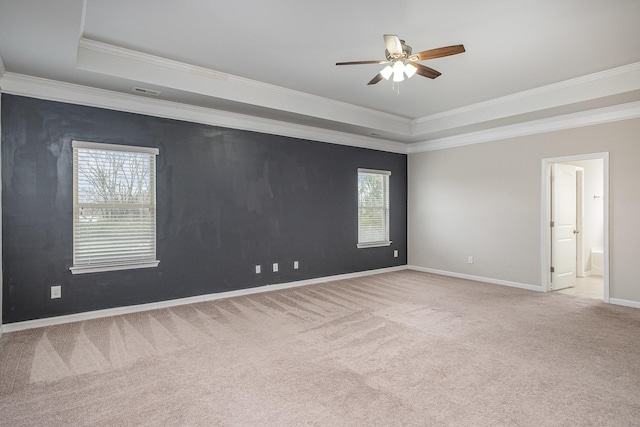 carpeted spare room with baseboards, a raised ceiling, a ceiling fan, and crown molding