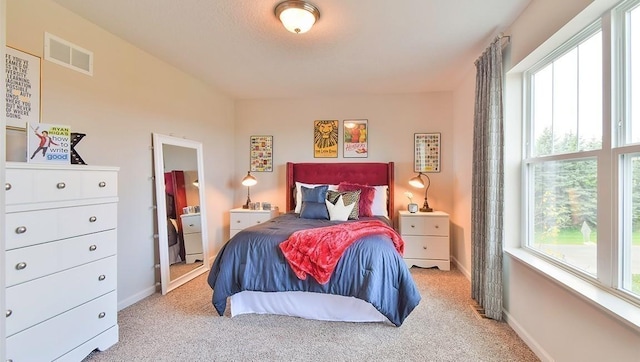 bedroom with light colored carpet, visible vents, and baseboards