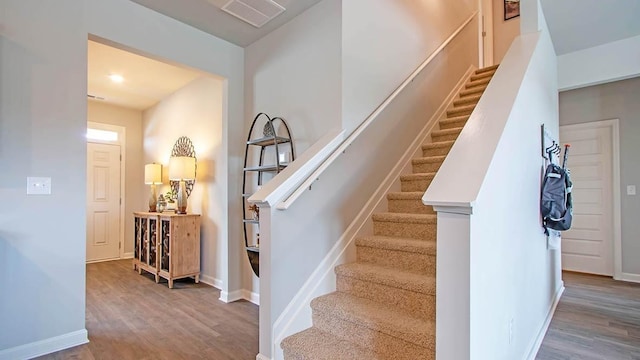 stairs featuring wood finished floors, visible vents, and baseboards