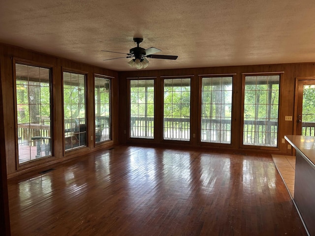 unfurnished sunroom featuring a wealth of natural light, visible vents, and a ceiling fan