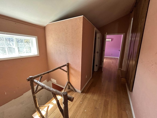 hallway with wood-type flooring, baseboards, and vaulted ceiling