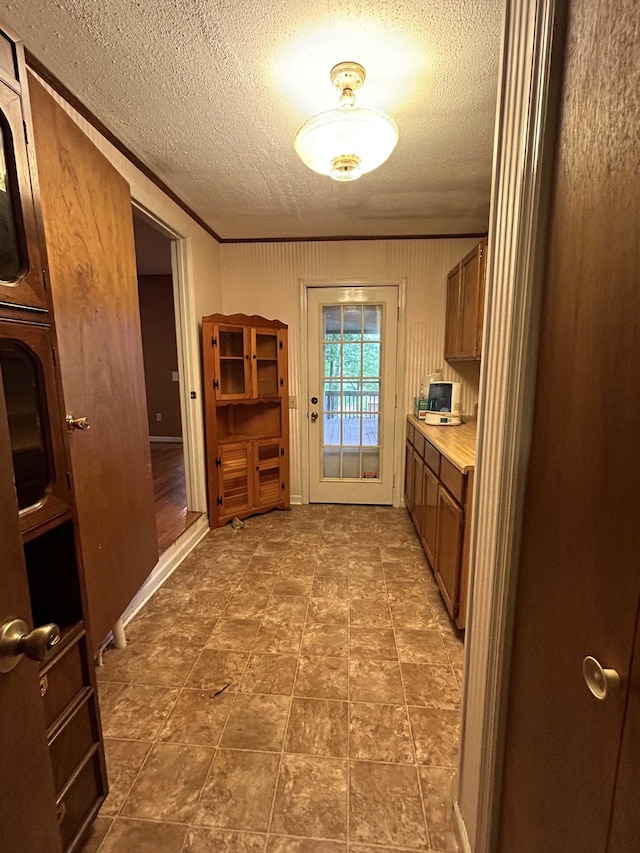 doorway to outside featuring a textured ceiling and crown molding