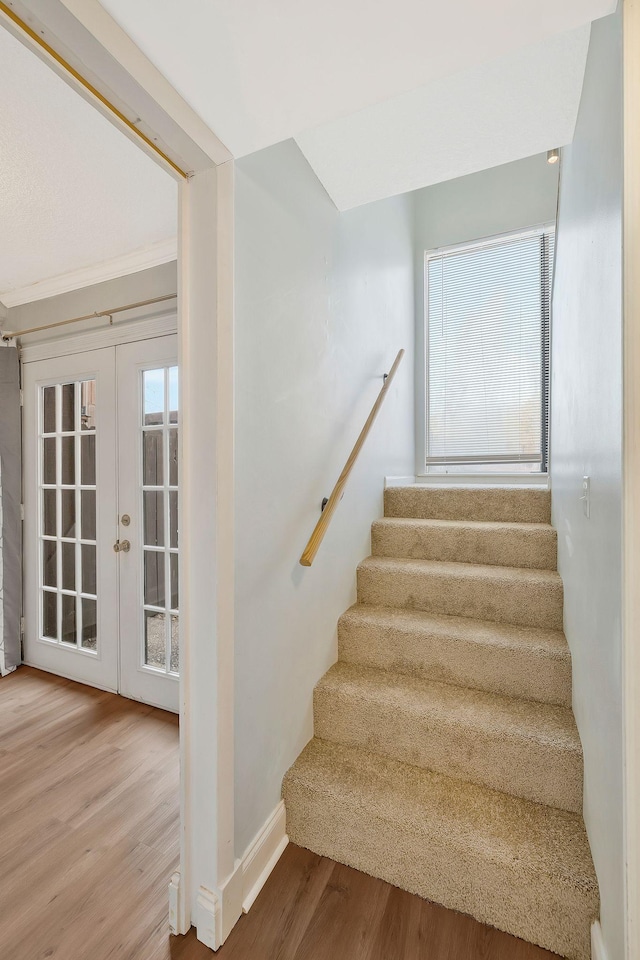 stairway featuring wood finished floors, baseboards, and french doors