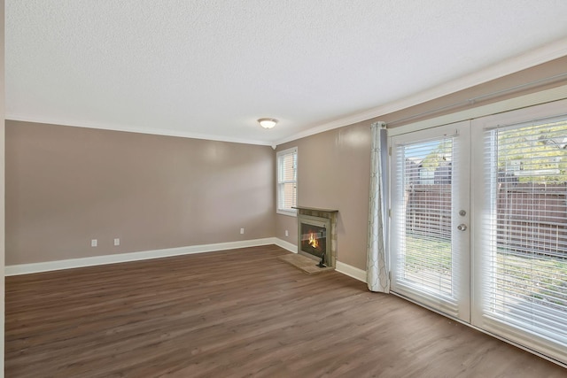 unfurnished living room with a glass covered fireplace, a textured ceiling, wood finished floors, and crown molding