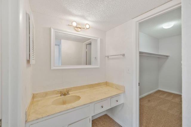 bathroom with baseboards, a textured ceiling, and vanity