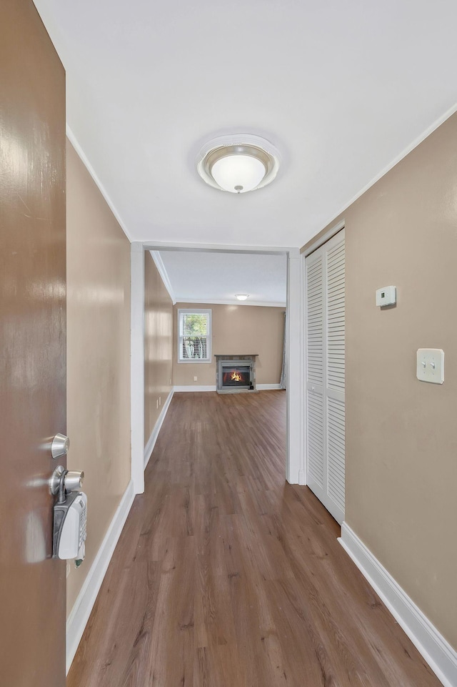 hall with wood finished floors, baseboards, and ornamental molding