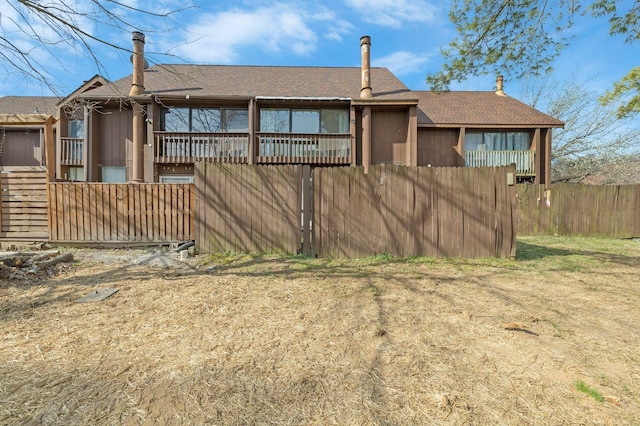 rear view of property featuring fence and roof with shingles