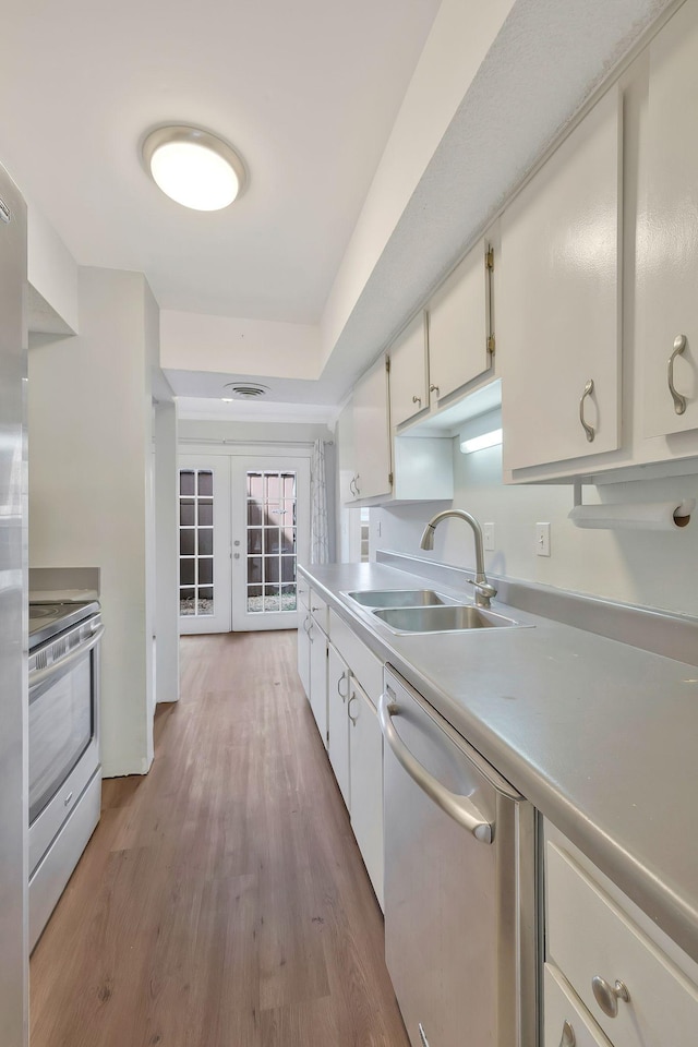 kitchen featuring a sink, wood finished floors, french doors, appliances with stainless steel finishes, and white cabinets