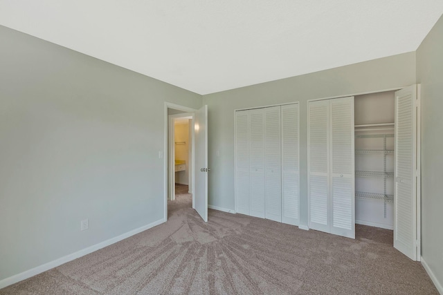 unfurnished bedroom featuring two closets, baseboards, and carpet floors