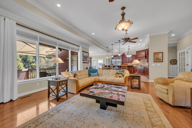 living room with light wood-type flooring, visible vents, ornamental molding, baseboards, and ceiling fan