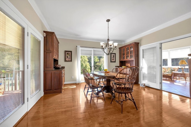 dining space with a notable chandelier, wood finished floors, and crown molding