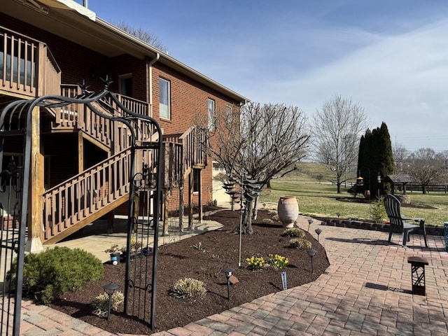 view of property exterior with stairway, a patio, and brick siding