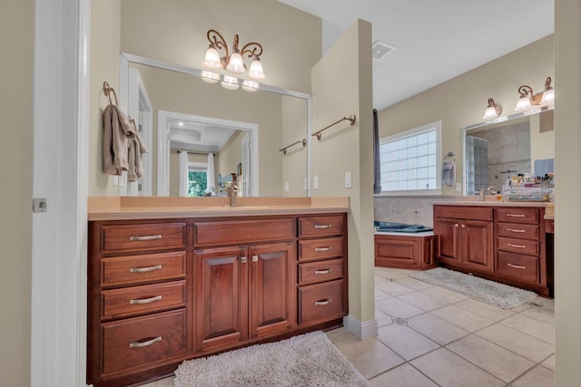 full bath with a tub to relax in, visible vents, two vanities, a sink, and tile patterned flooring