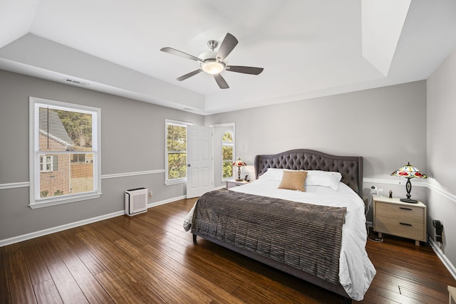 bedroom featuring baseboards, visible vents, a tray ceiling, ceiling fan, and hardwood / wood-style flooring