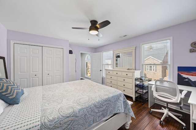 bedroom with a closet, visible vents, multiple windows, and dark wood-style flooring