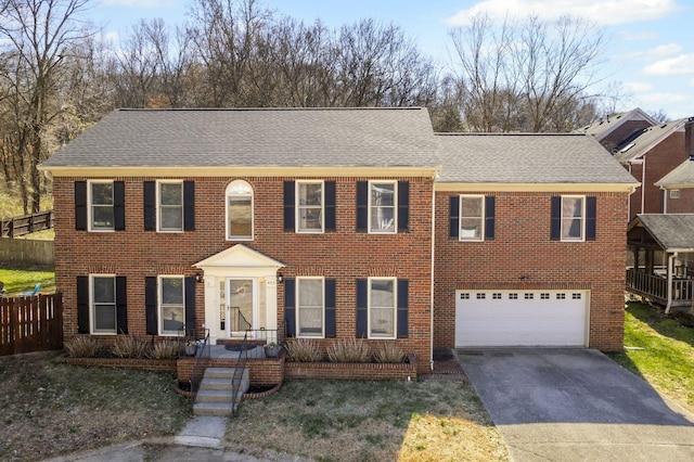 view of front of property with fence, an attached garage, a shingled roof, concrete driveway, and brick siding