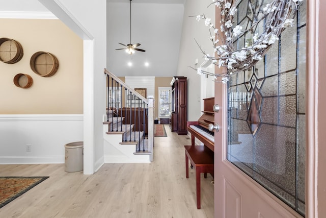 entrance foyer featuring light wood-type flooring, ornamental molding, a ceiling fan, baseboards, and stairs