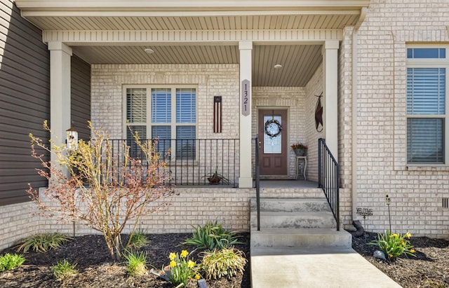 doorway to property with brick siding and covered porch