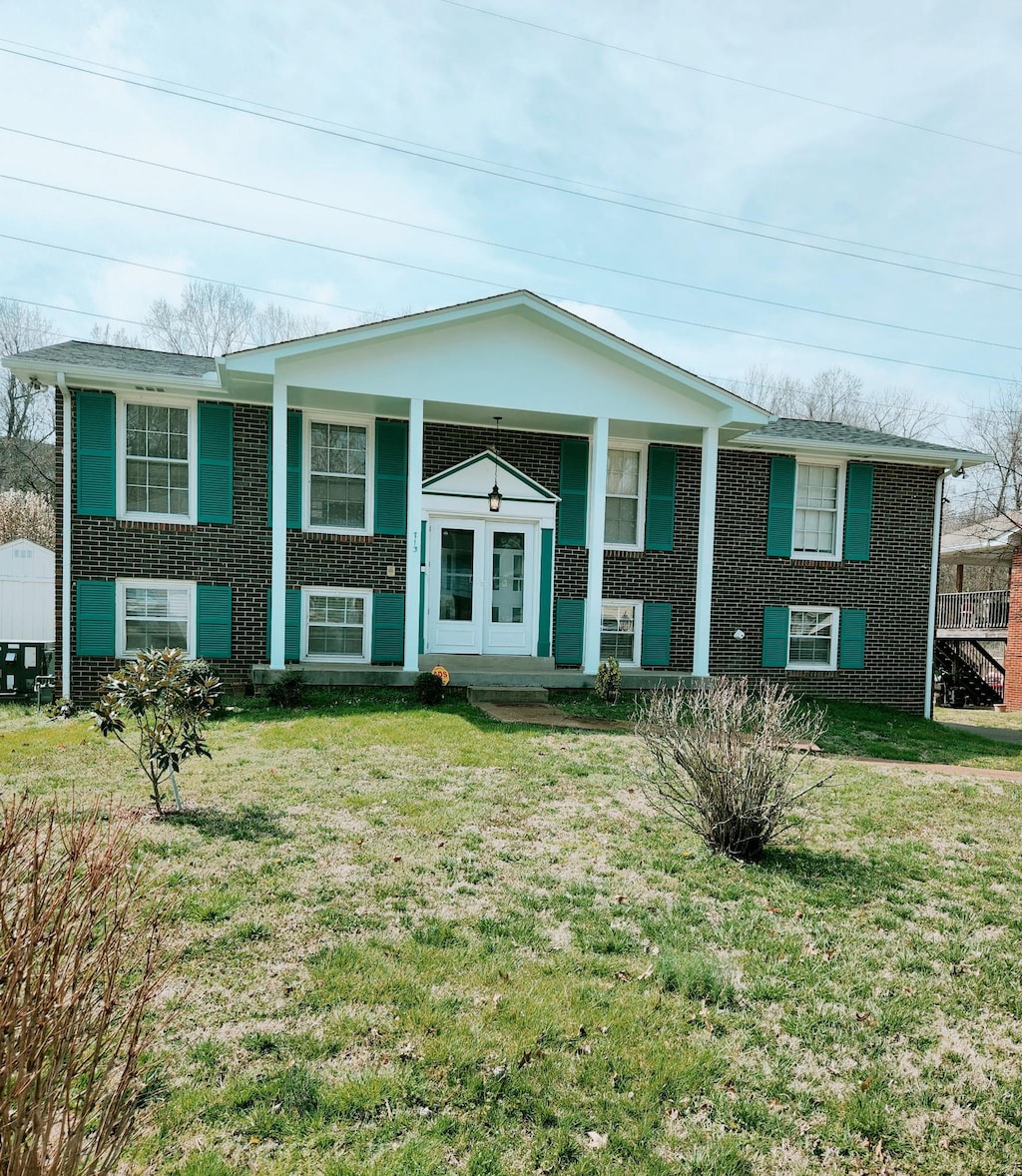 split foyer home with brick siding, a porch, and a front yard