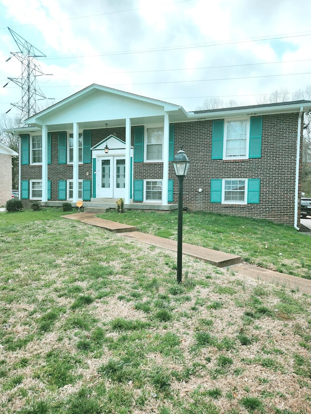 bi-level home featuring a front lawn, covered porch, and brick siding