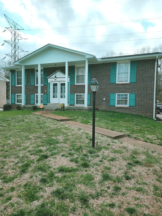 bi-level home with brick siding, a porch, and a front lawn