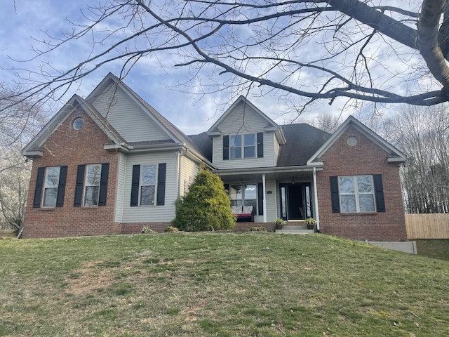 traditional-style house with a front lawn, fence, covered porch, and brick siding