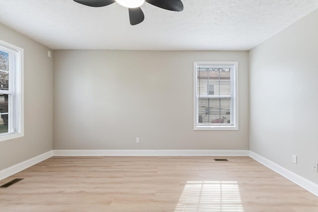 spare room with visible vents, plenty of natural light, and ceiling fan