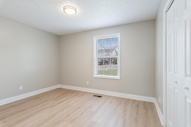 unfurnished bedroom with light wood-style flooring, baseboards, visible vents, and a closet