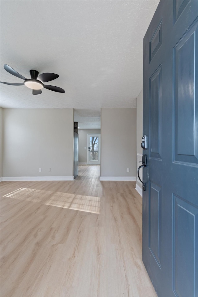 entryway with light wood finished floors, a textured ceiling, baseboards, and a ceiling fan