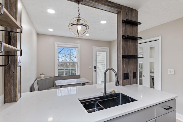 kitchen with open shelves, light countertops, recessed lighting, a notable chandelier, and a sink